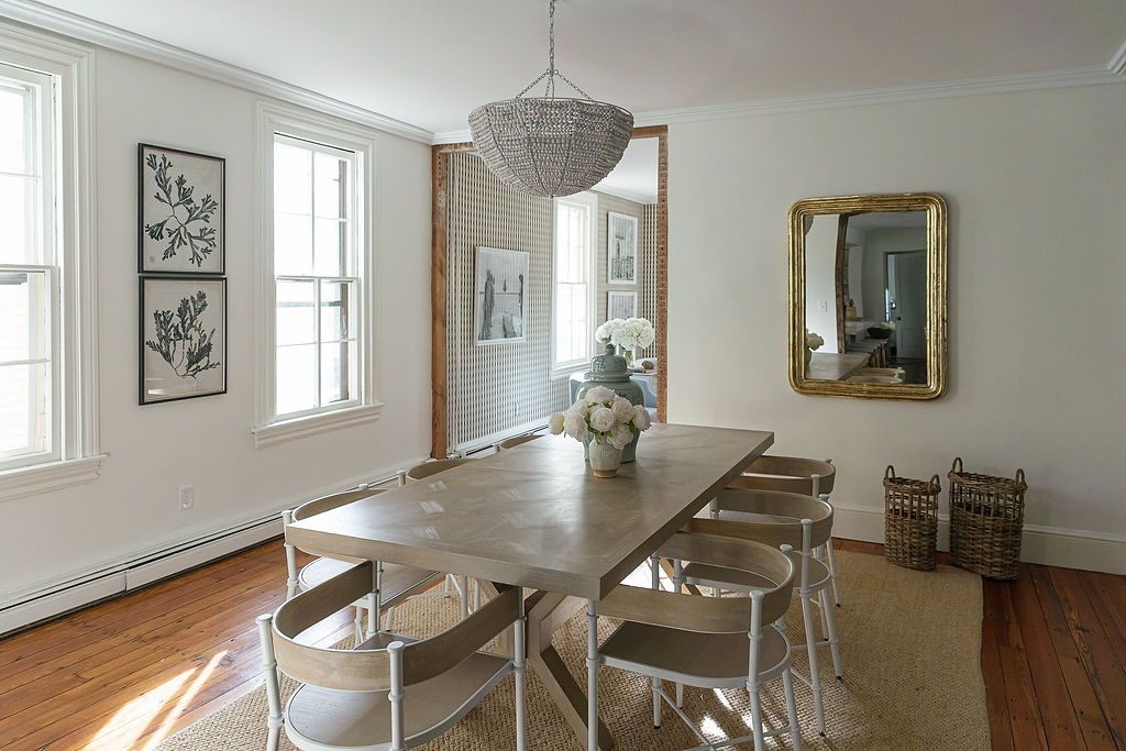 Contemporary white dining room with crystal chandelier features hardwood floors and multiple windows for natural light.