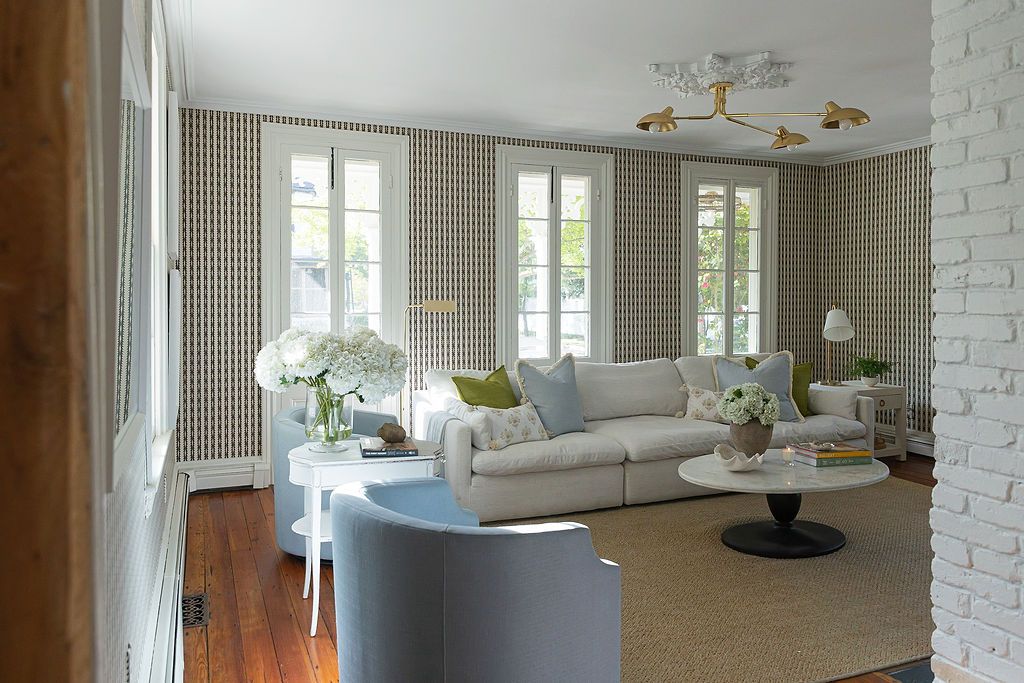 Modern bright interior room with brick walls, large windows, and gray furniture showcases an open-concept living space.