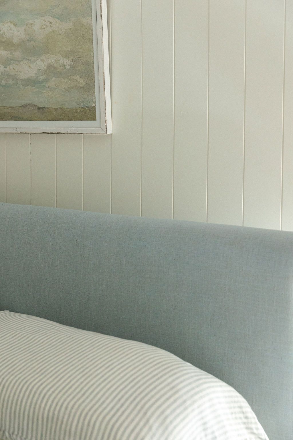 A minimalist interior scene showing a curved light blue couch or sofa against a white paneled wall.