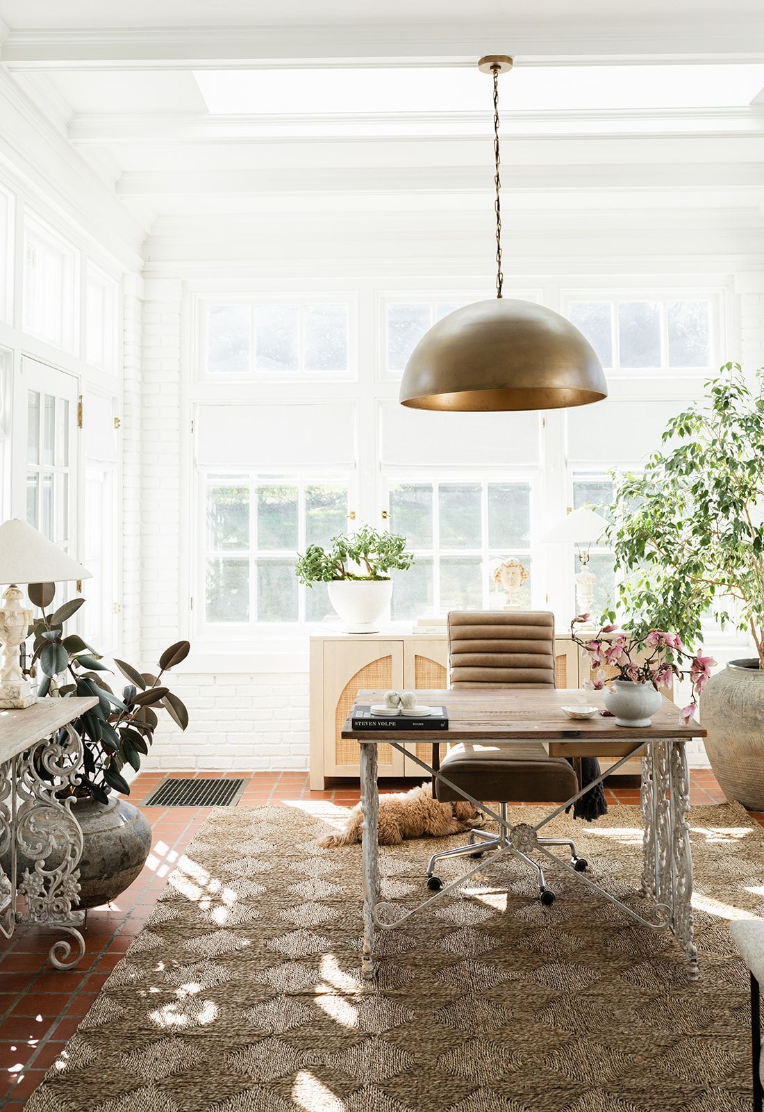 Bright workspace with dome pendant light, office chair, and natural light streaming through large windows.
