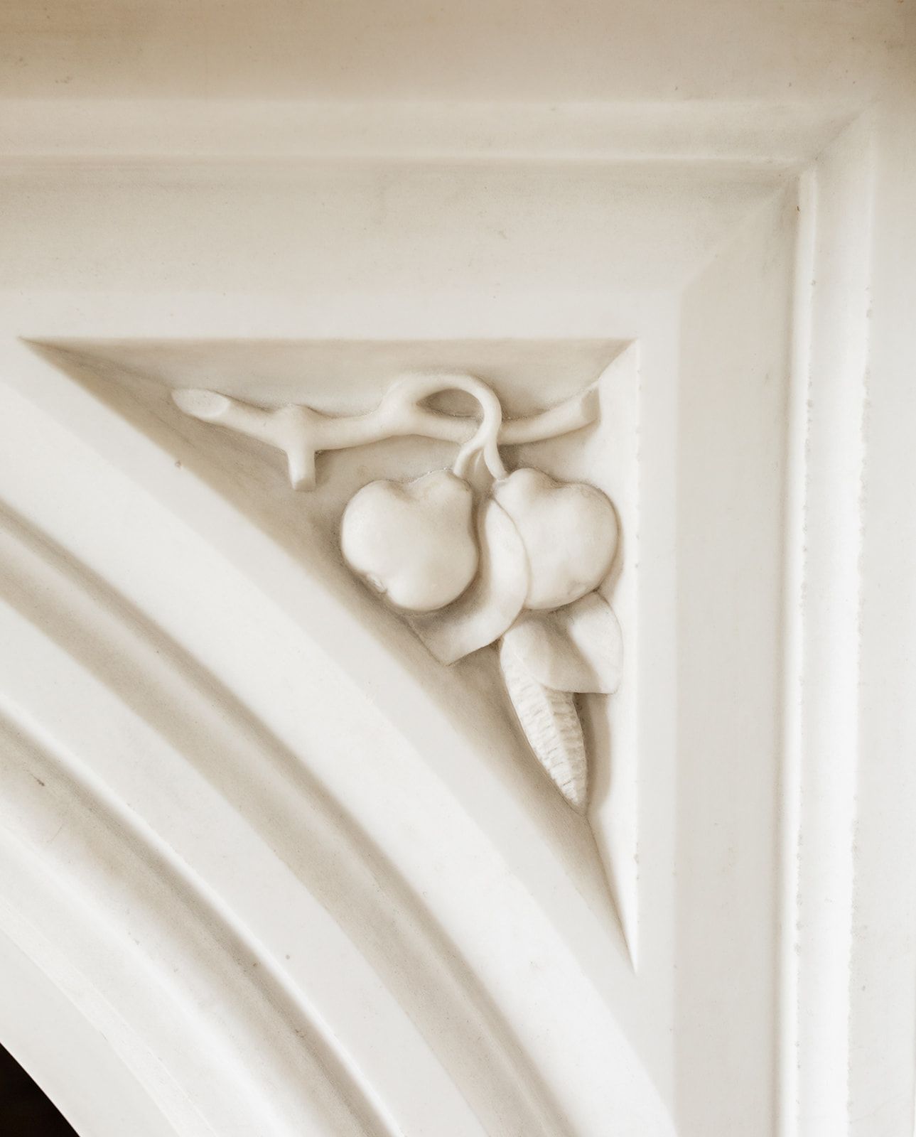 Ornate white plaster architectural detail showing decorative fruit molding in a corner of classical trim work.
