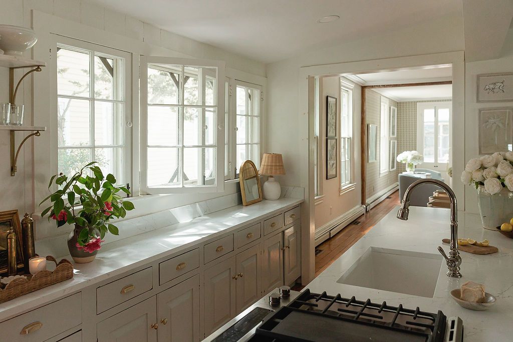 Bright white kitchen with gothic arch windows, gray cabinets, and a counter-to-ceiling bank of windows letting in natural light.