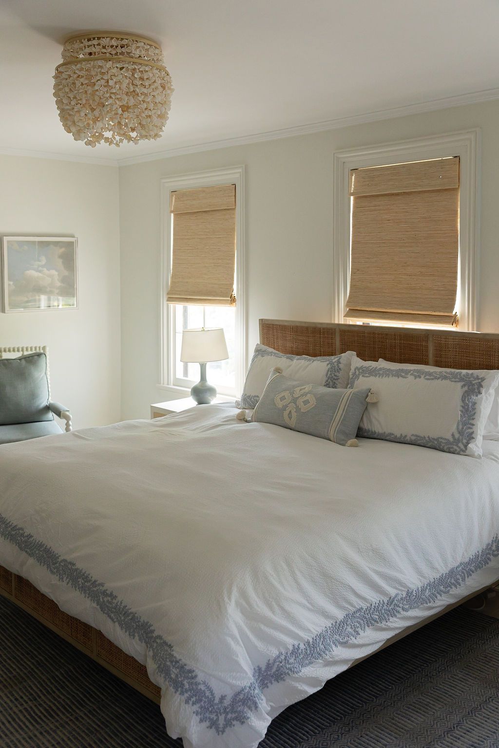 Serene bedroom with beaded chandelier, wooden bed frame, and woven bamboo window shades.