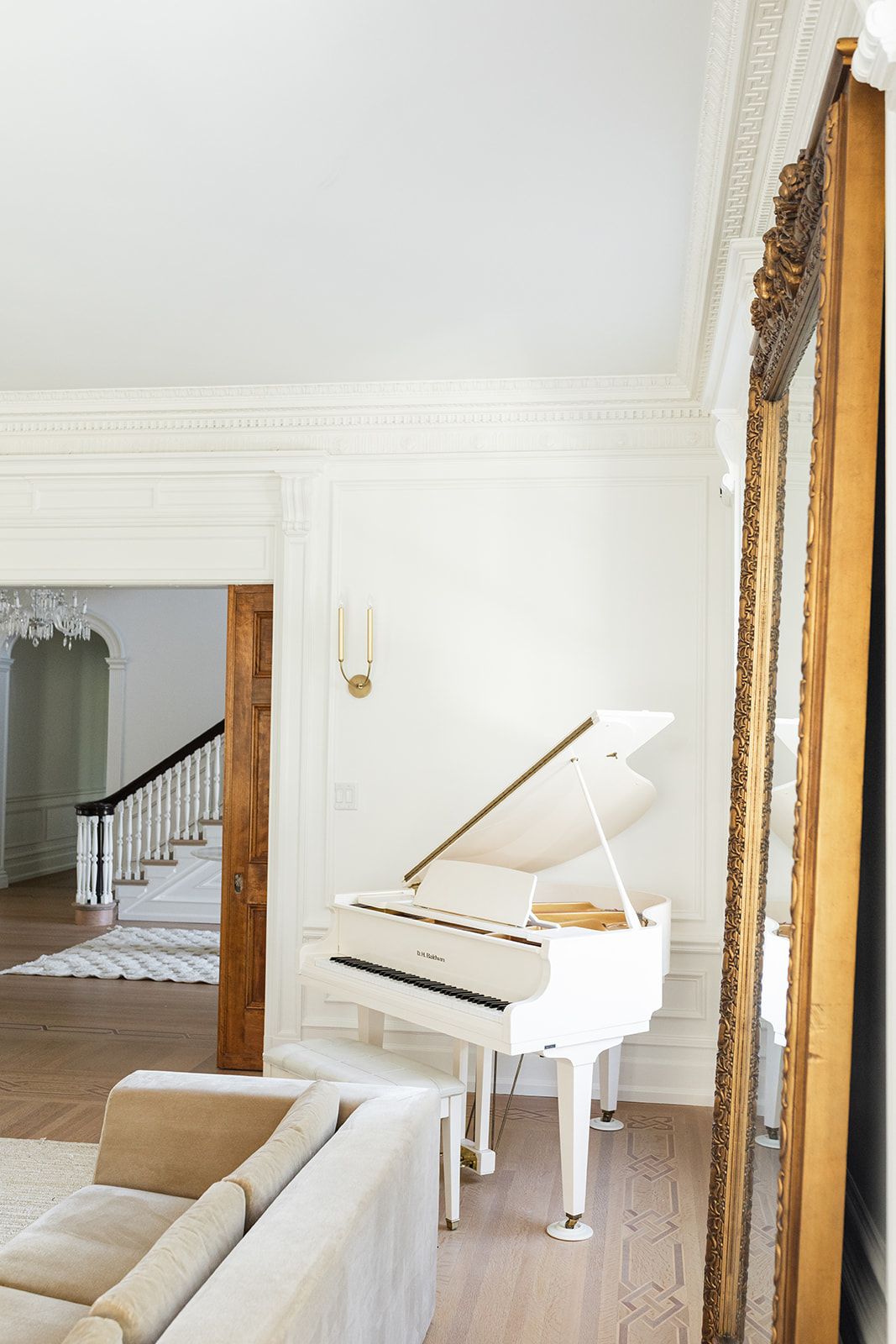 White grand piano positioned near wooden doorway in bright, minimalist interior.