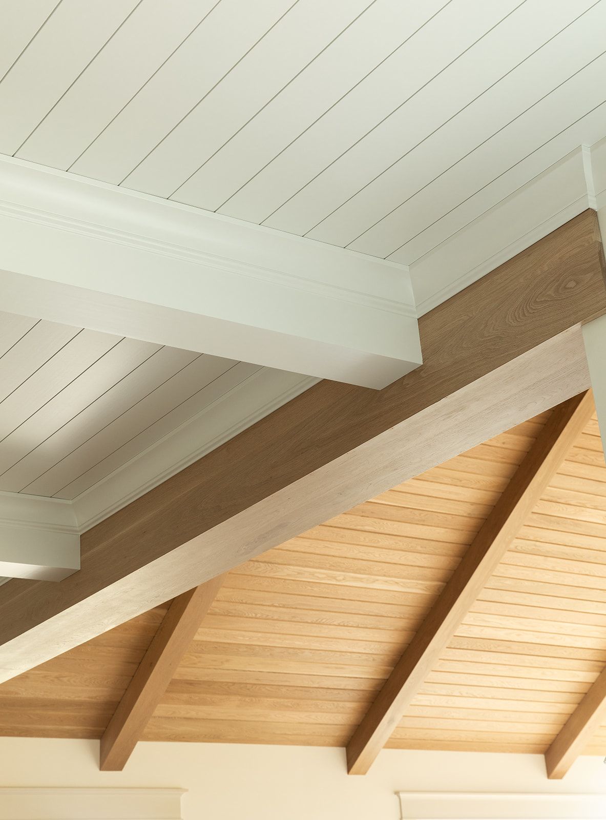 Vaulted ceiling with natural wood beams and white painted tongue-and-groove planks in a modern farmhouse interior.