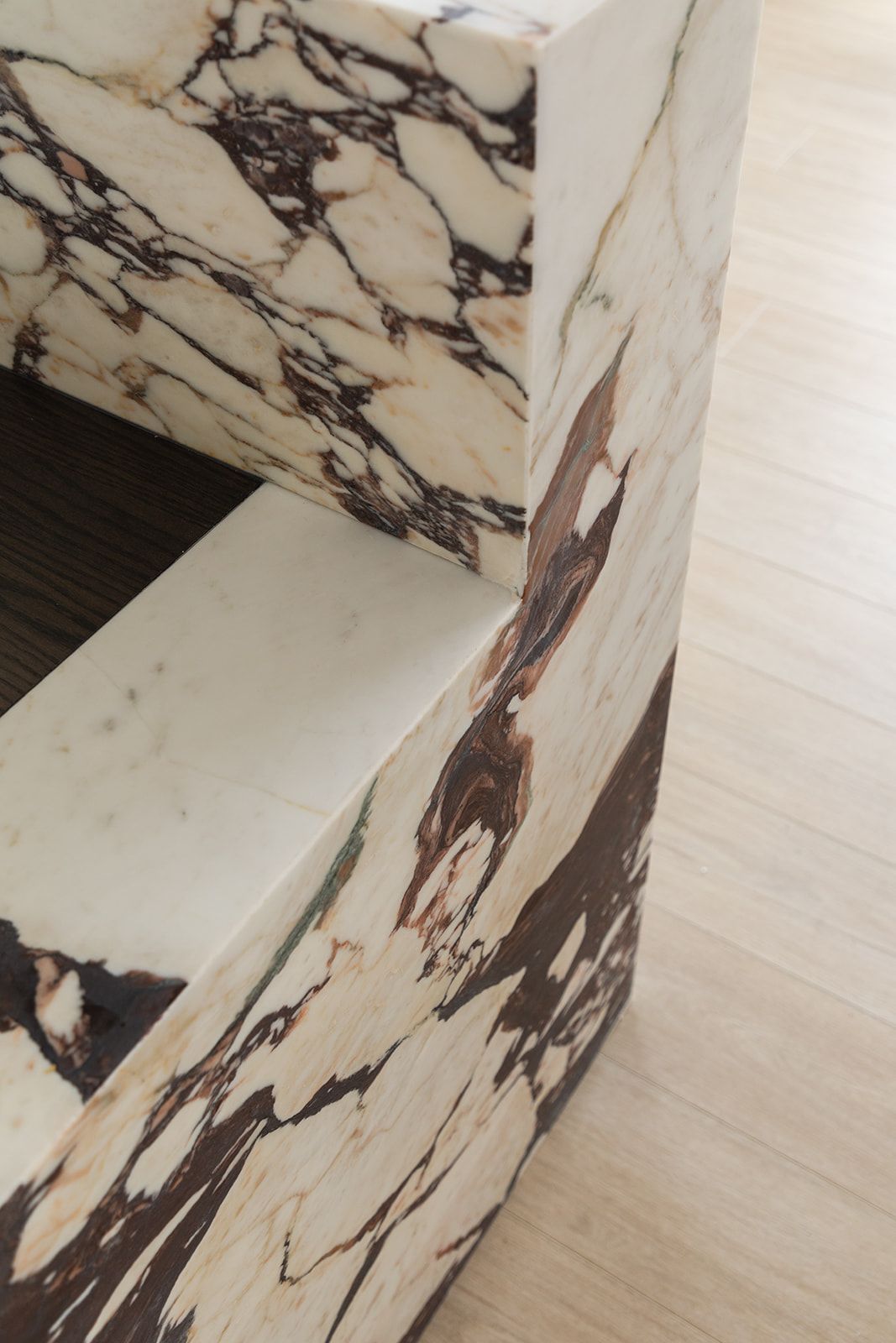 Marble counter and wall featuring dramatic black and brown veining patterns against cream colored stone surfaces.