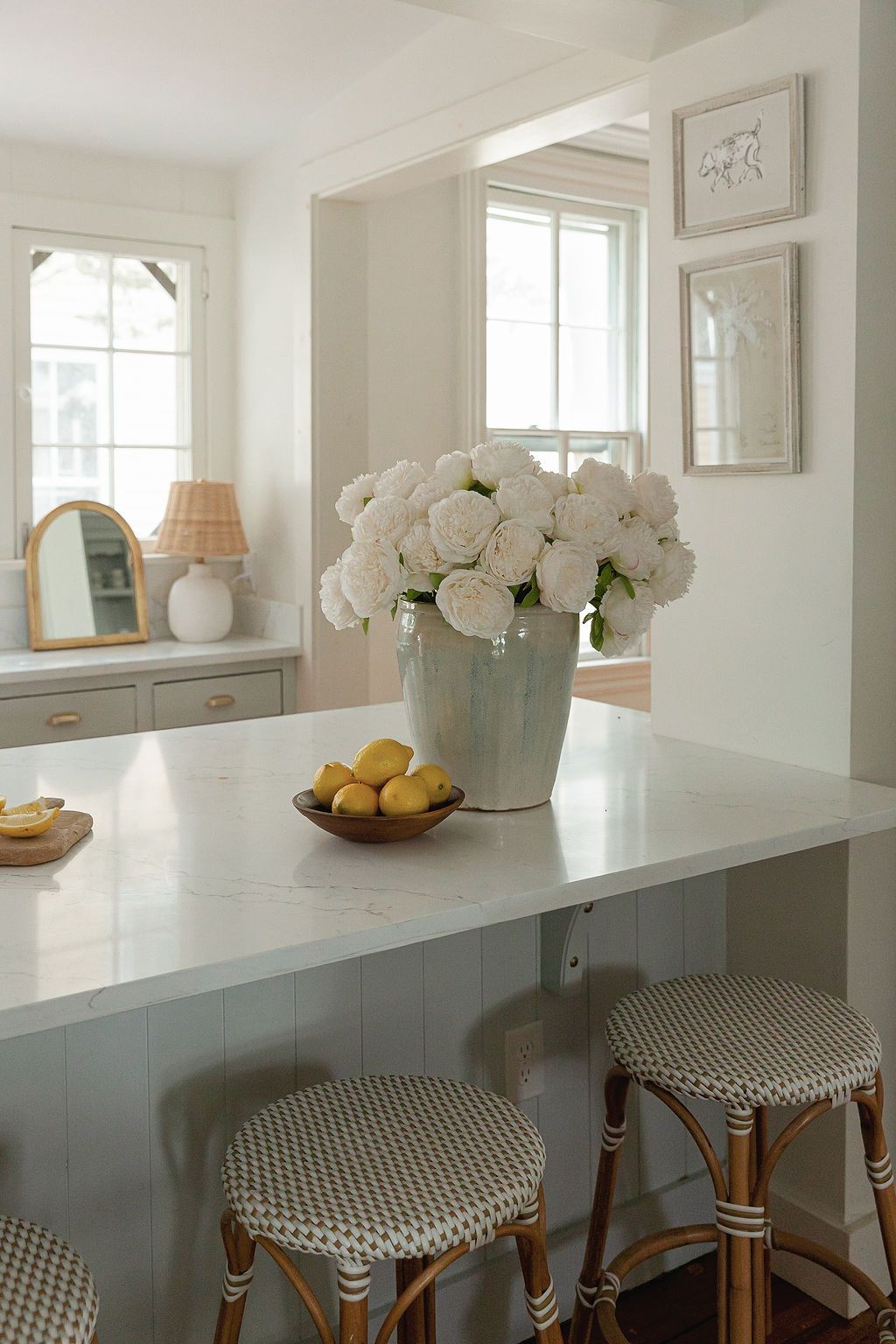 Elegant kitchen with white flowers, bistro stools, and marble countertop island.