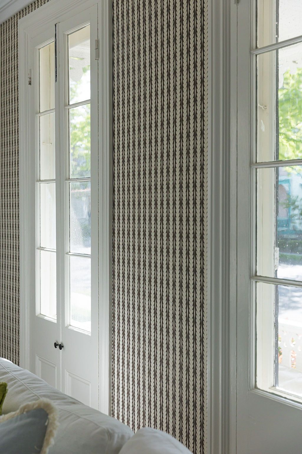 A light-filled room with floor-to-ceiling windows featuring a modern geometric patterned wallpaper design.