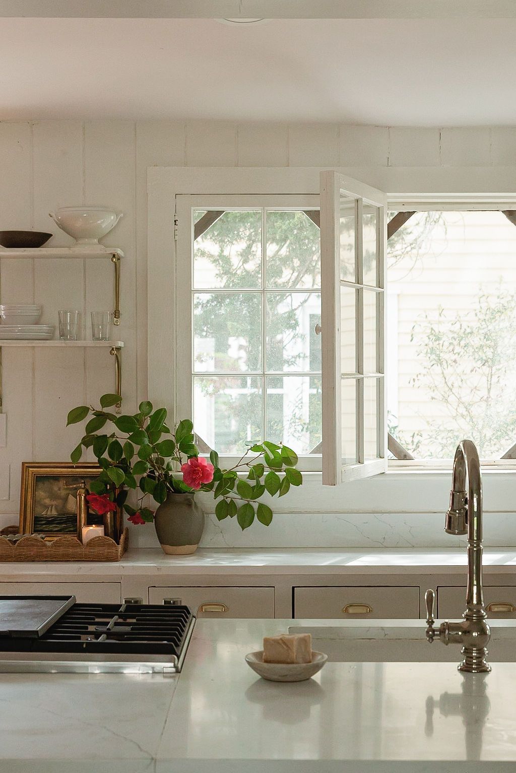 White modern kitchen counter with windows and houseplants showing sunlight streaming in from multiple angles.