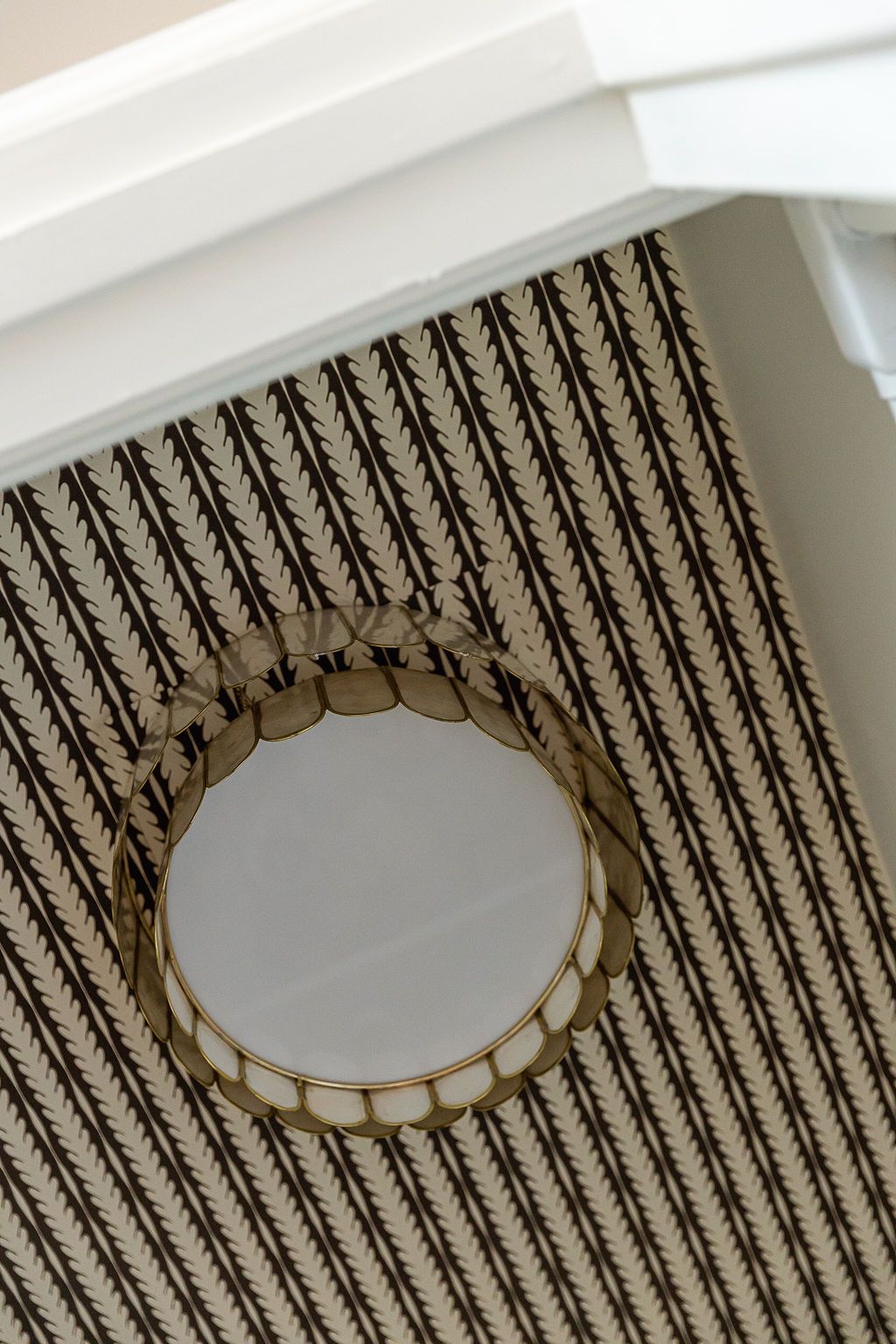 A black and white striped geometric wallpaper pattern surrounds a circular white recessed ceiling light fixture.