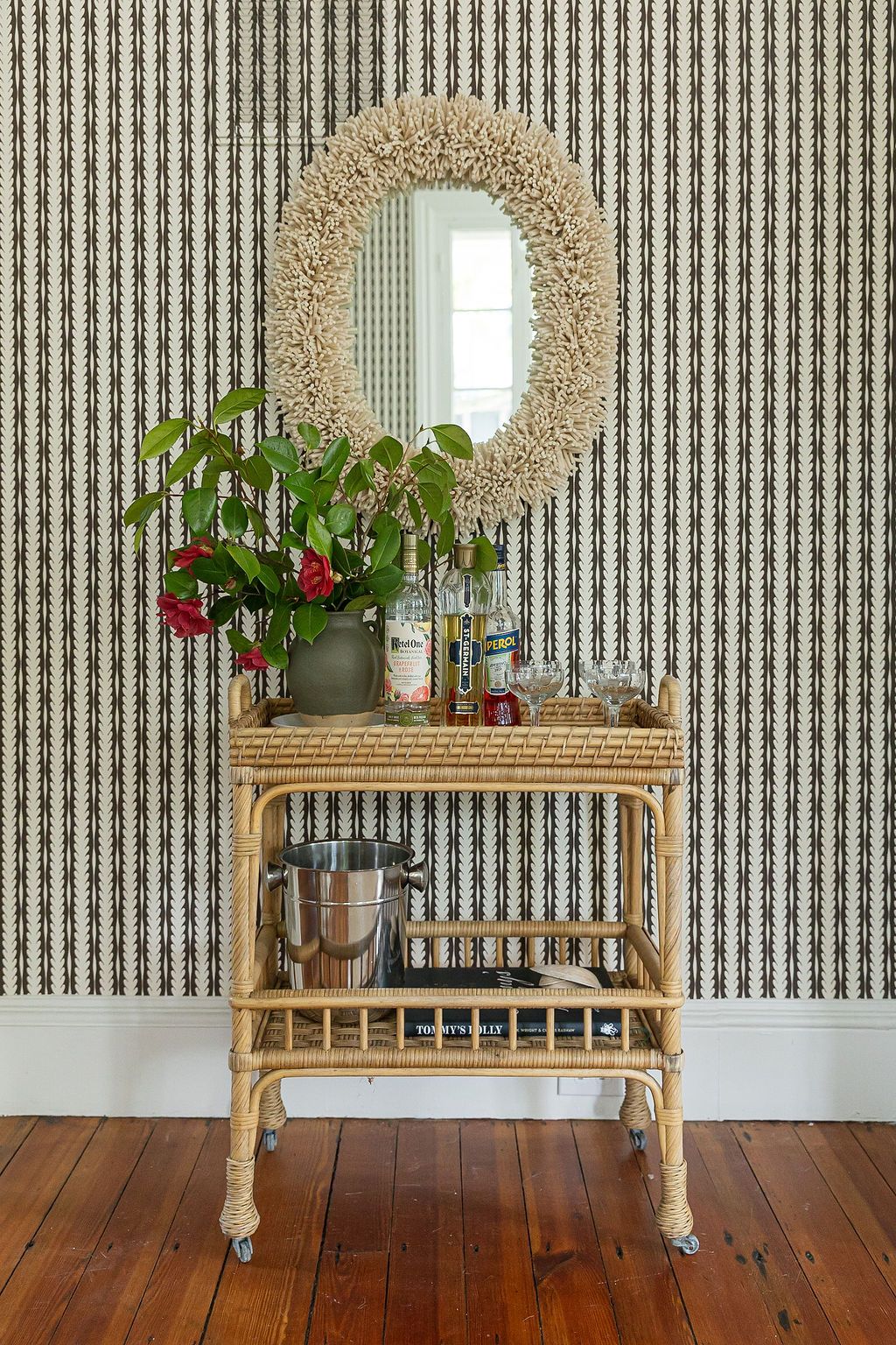 Three identical rattan benches with round woven mirrors above them sit against a striped wallpaper in a rustic room.