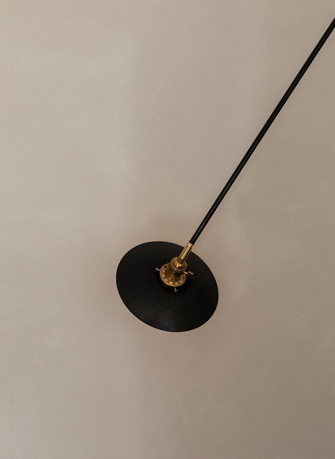 Overhead view of a black and gold ceiling light fixture against a beige background.