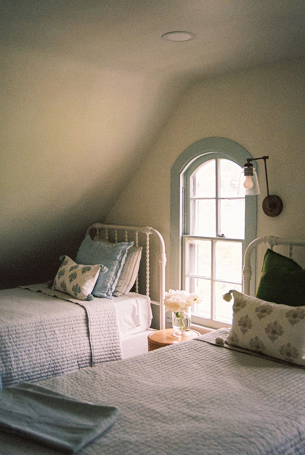 A cozy attic bedroom with white bedding and arched windows shows different angles of the same peaceful space.