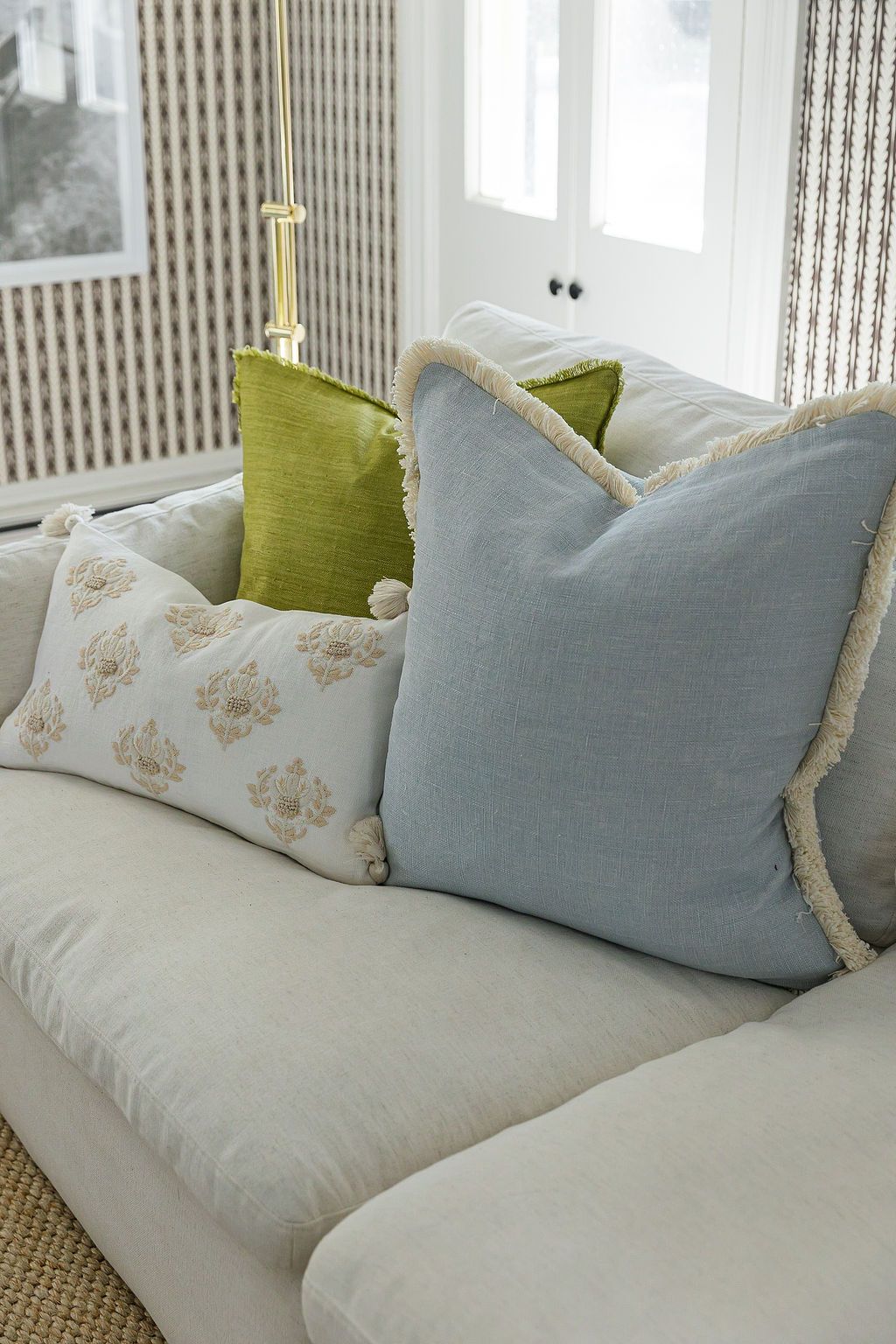 Comfortable white couch adorned with decorative throw pillows in pale blue, lime green, and floral patterns.