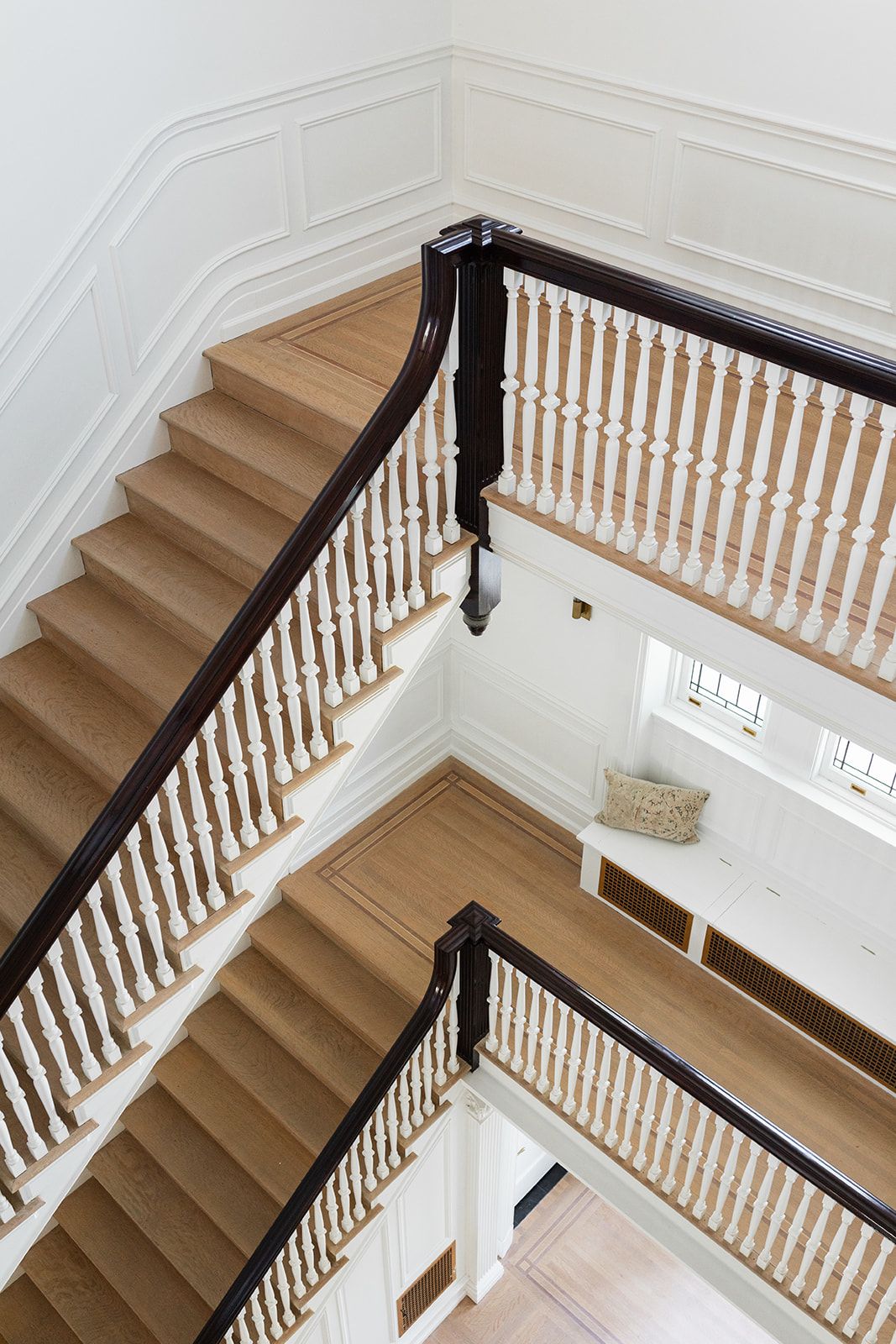 Grand staircase with white balusters and wooden handrails viewed from above in a traditional home.