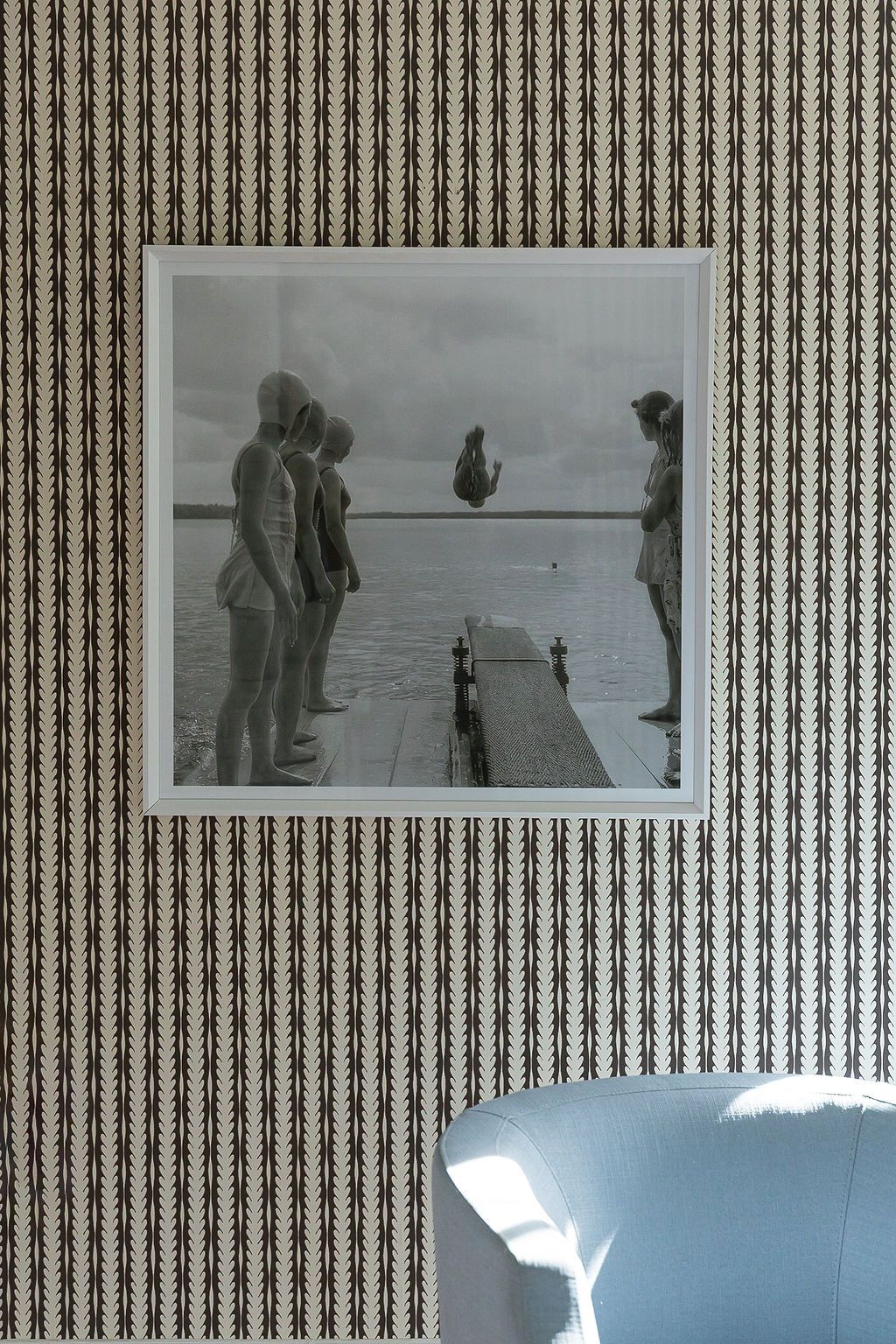 A vintage black and white photograph shows people gathered on a diving board or dock over water on a cloudy day.
