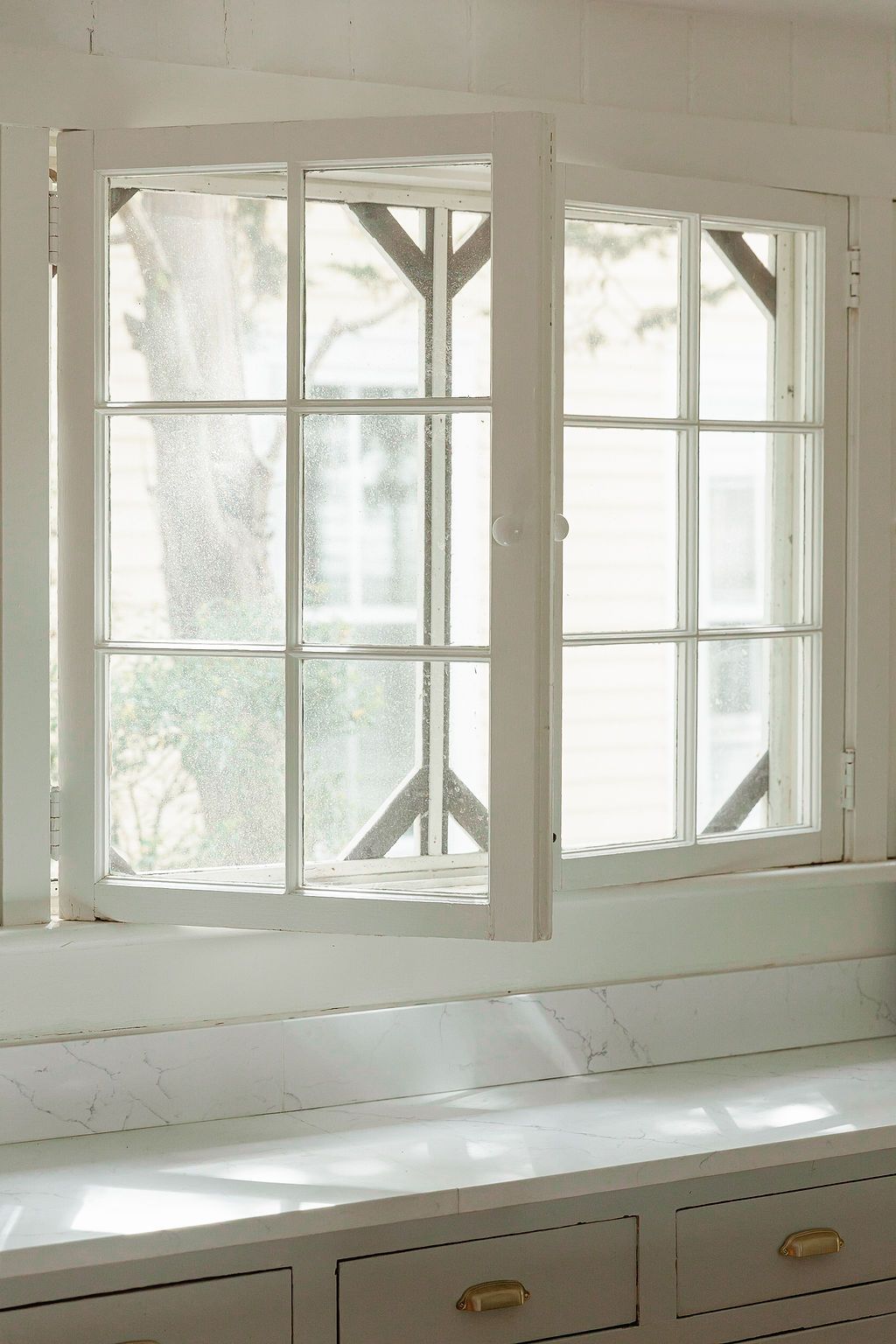 Built-in white drawers beneath a row of bright windows let natural light stream into an airy interior space.