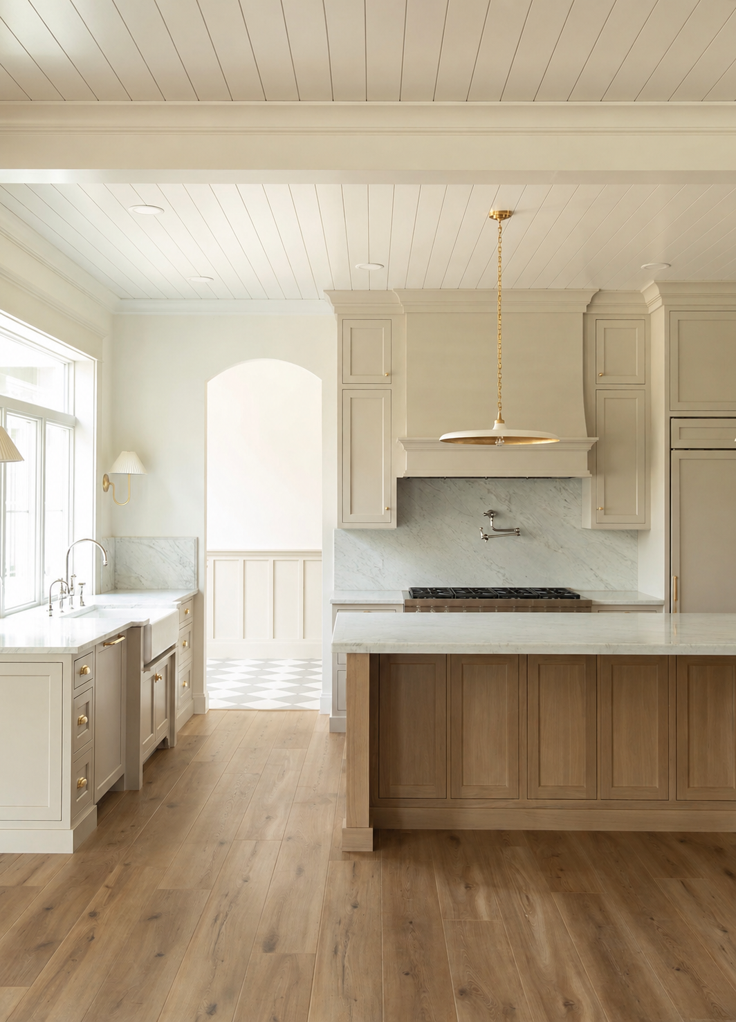 Elegant kitchen with beige cabinets, wood island, marble backsplash, brass pendant light, and light hardwood floors.