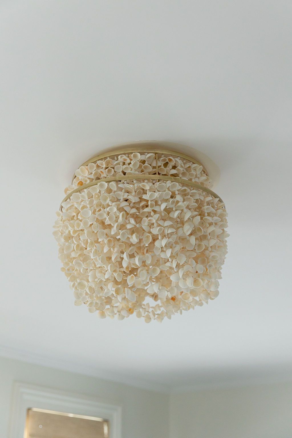 Ornate capiz shell flush mount ceiling light fixture in cream tones against a white ceiling.