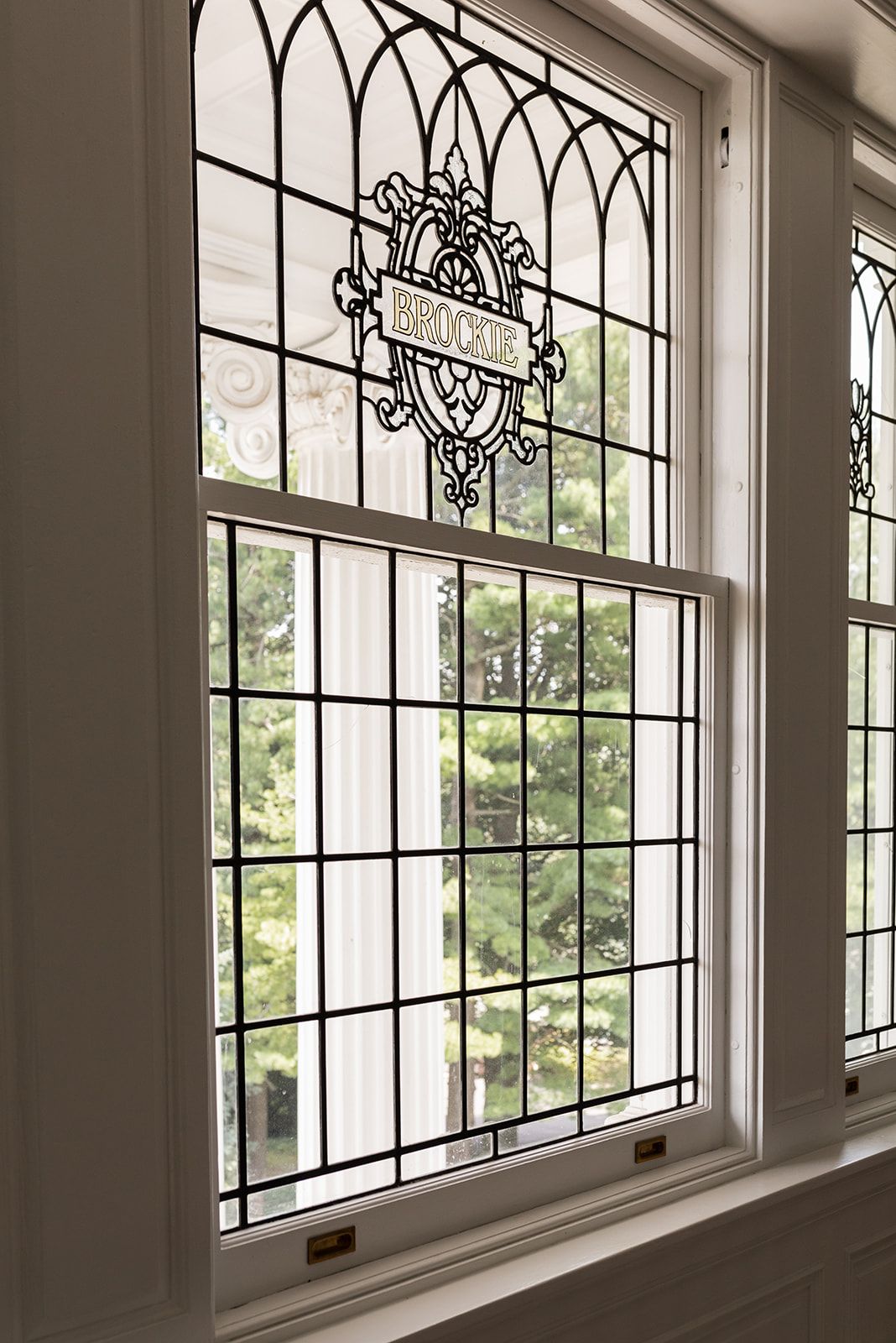 Elegant ornamental leaded glass windows with decorative ironwork patterns line a bright white interior wall.