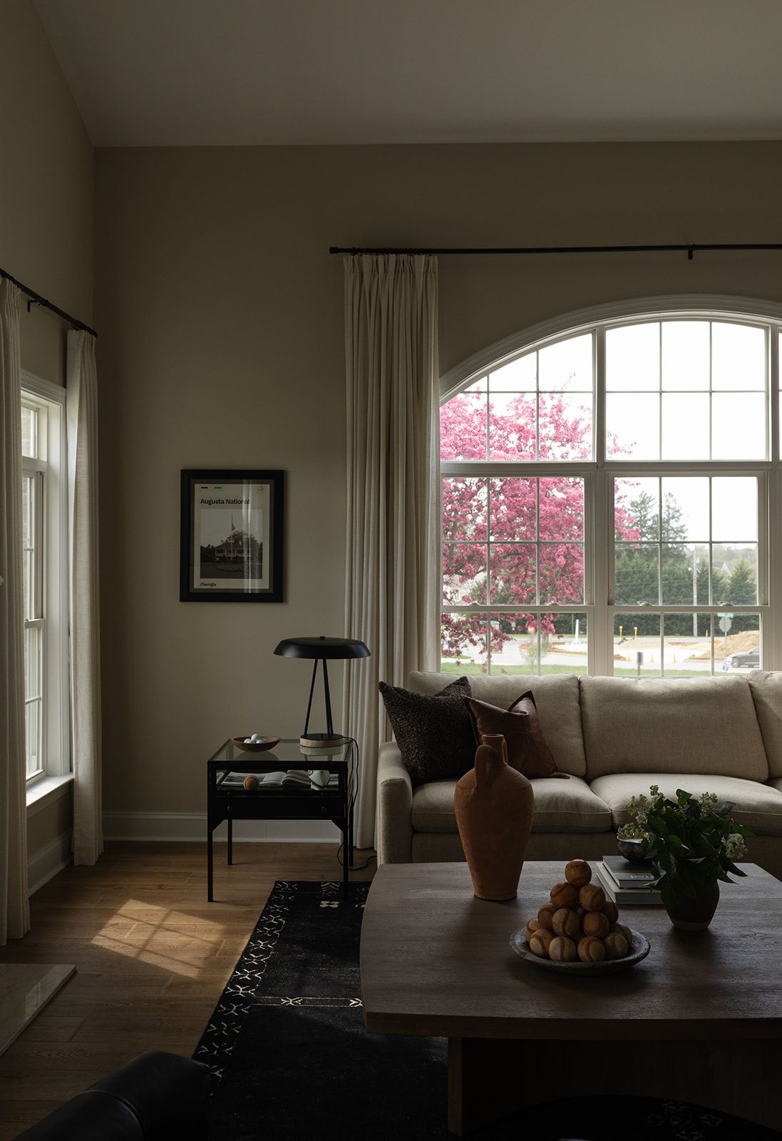 Panoramic view of a contemporary living space with dark flooring, curved windows, and minimal furnishings.