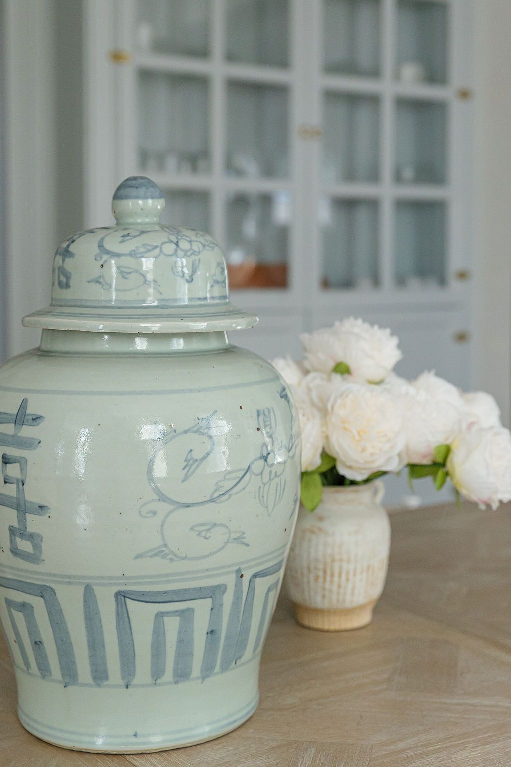 Four vintage Chinese celadon glazed ceramic bowls with blue decorative patterns arranged on a wooden surface with white flowers.