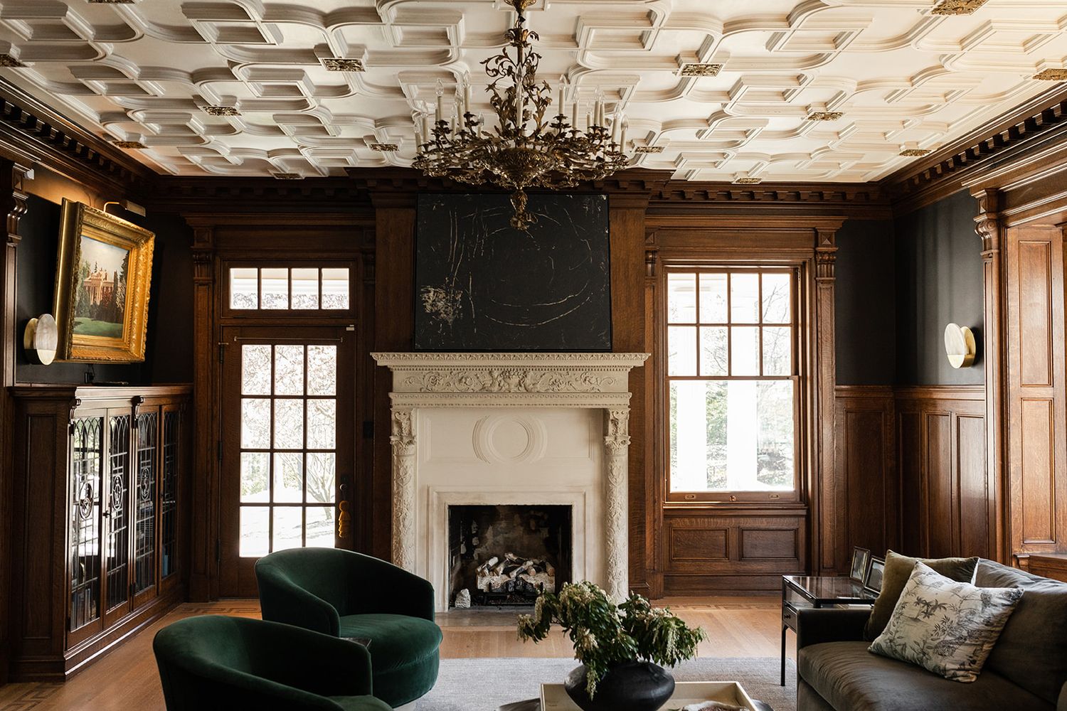 Luxurious room with coffered ceiling, dark wood paneling, emerald velvet chair, and fireplace.
