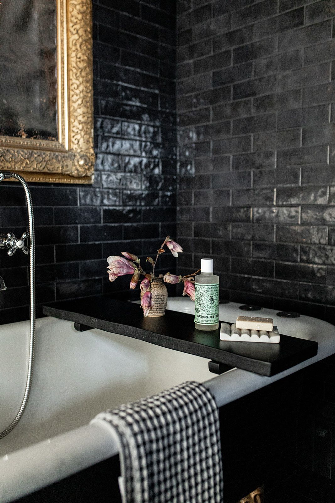 Black and white bathroom detail with checkered towel and decorative shelf on bathtub ledge.