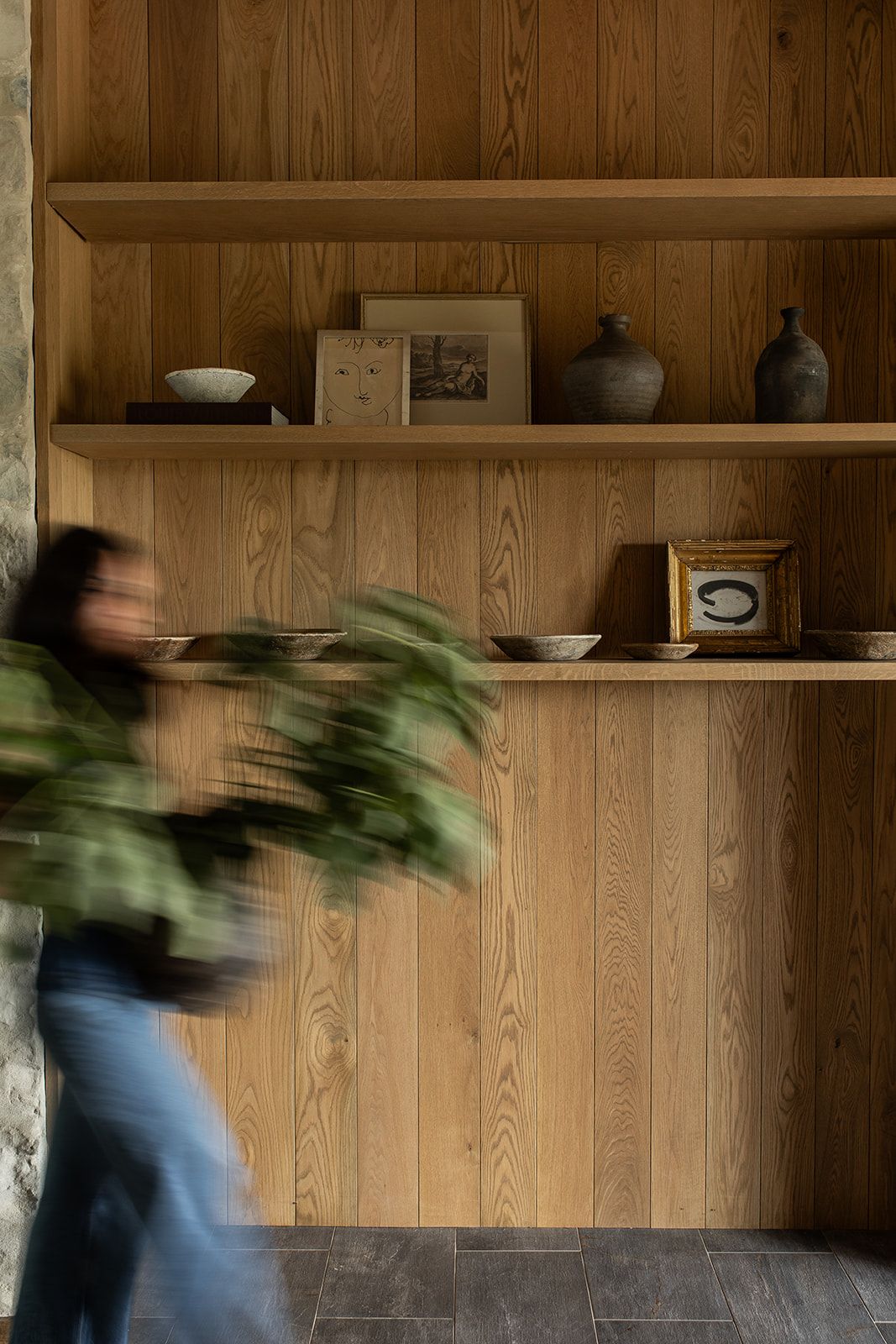 A motion blur sequence showing someone spinning with a green plant against a wooden wall with shelves.