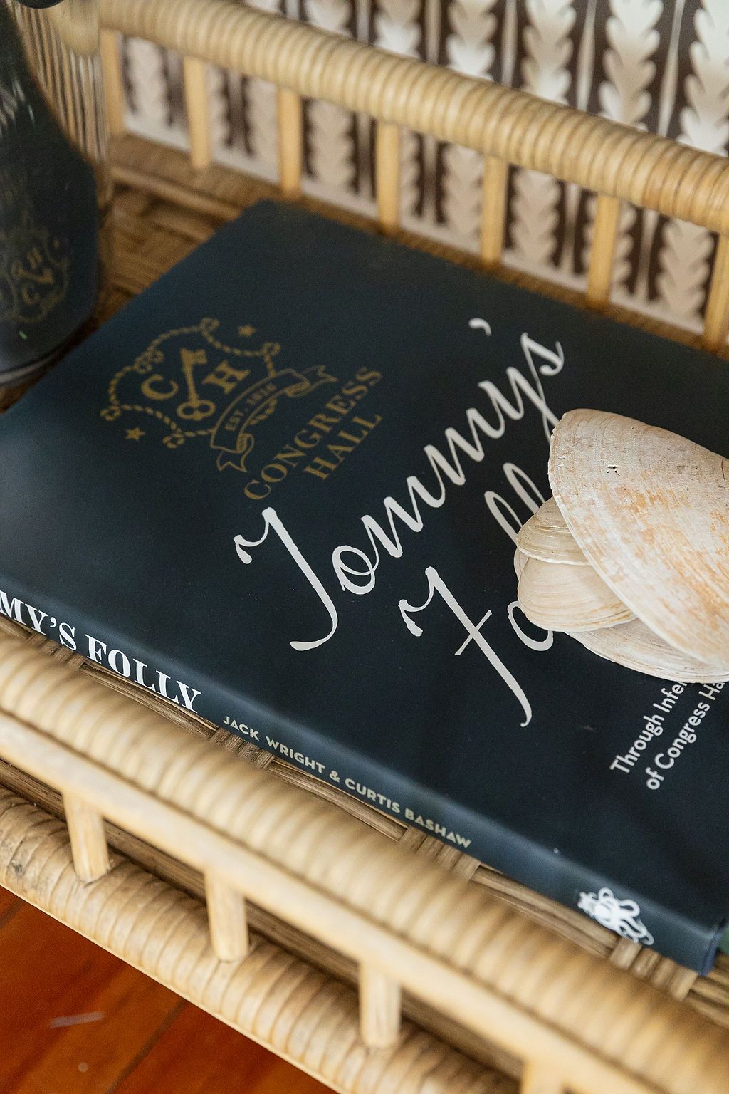 A dark hardcover copy of Tommy Fox book lying on a wooden surface with rattan or bamboo details.