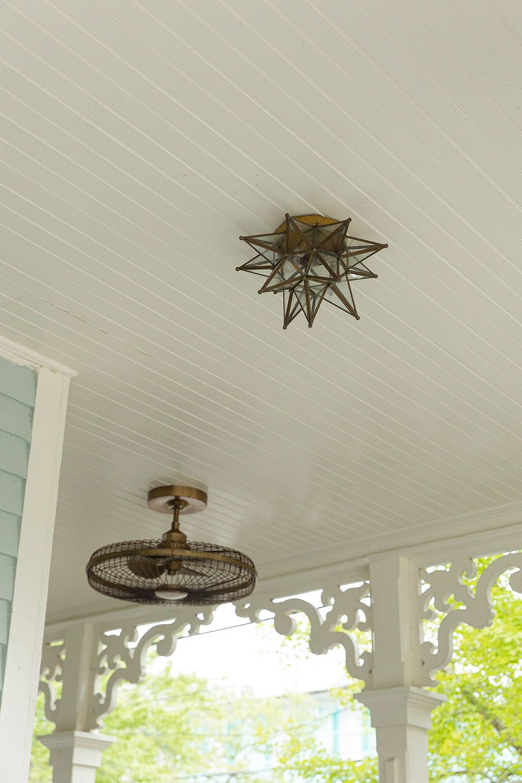 Decorative star-shaped pendant light fixture mounted on a white porch ceiling with detailed trim.