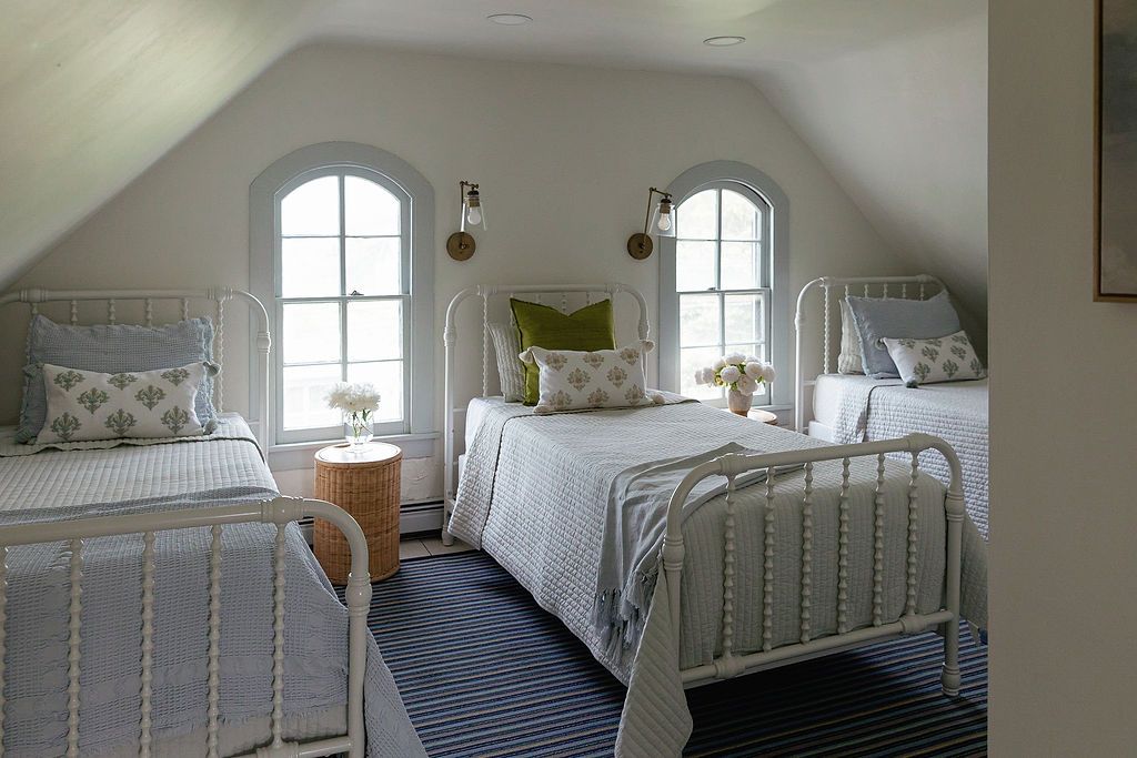 White minimalist bedroom with metal bed frame, matching side tables, and elegant window treatments in natural light.