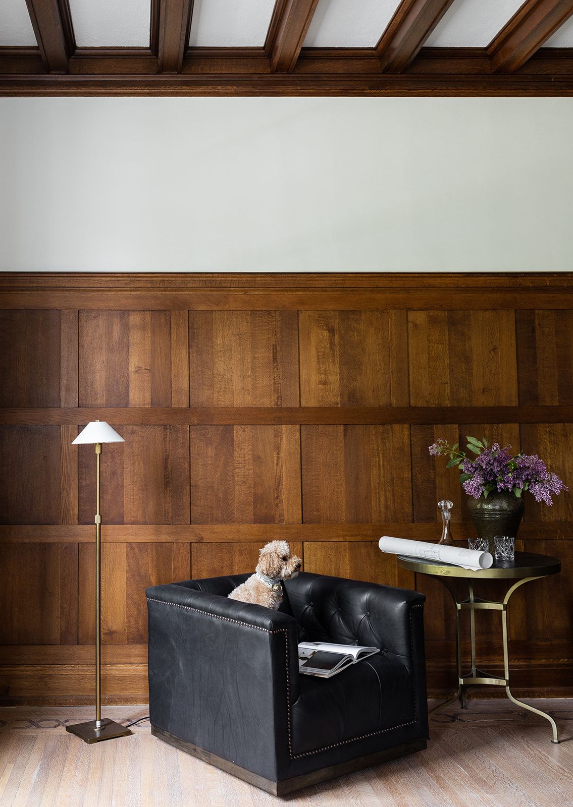 Modern room with wood paneling, black leather chair, and floor lamp beside simple side table.