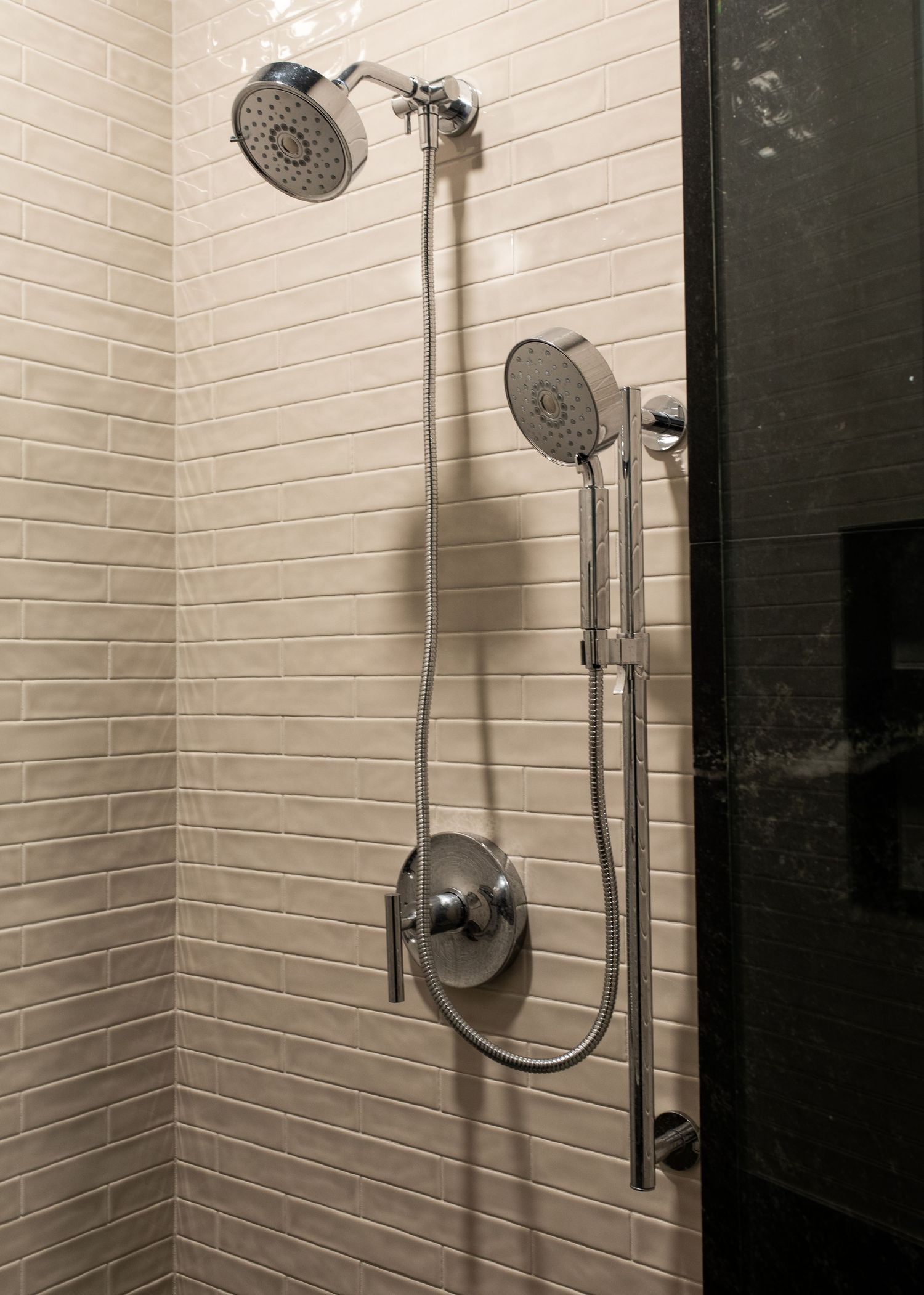 Modern bathroom interior featuring white subway tile walls and sleek chrome shower fixtures.