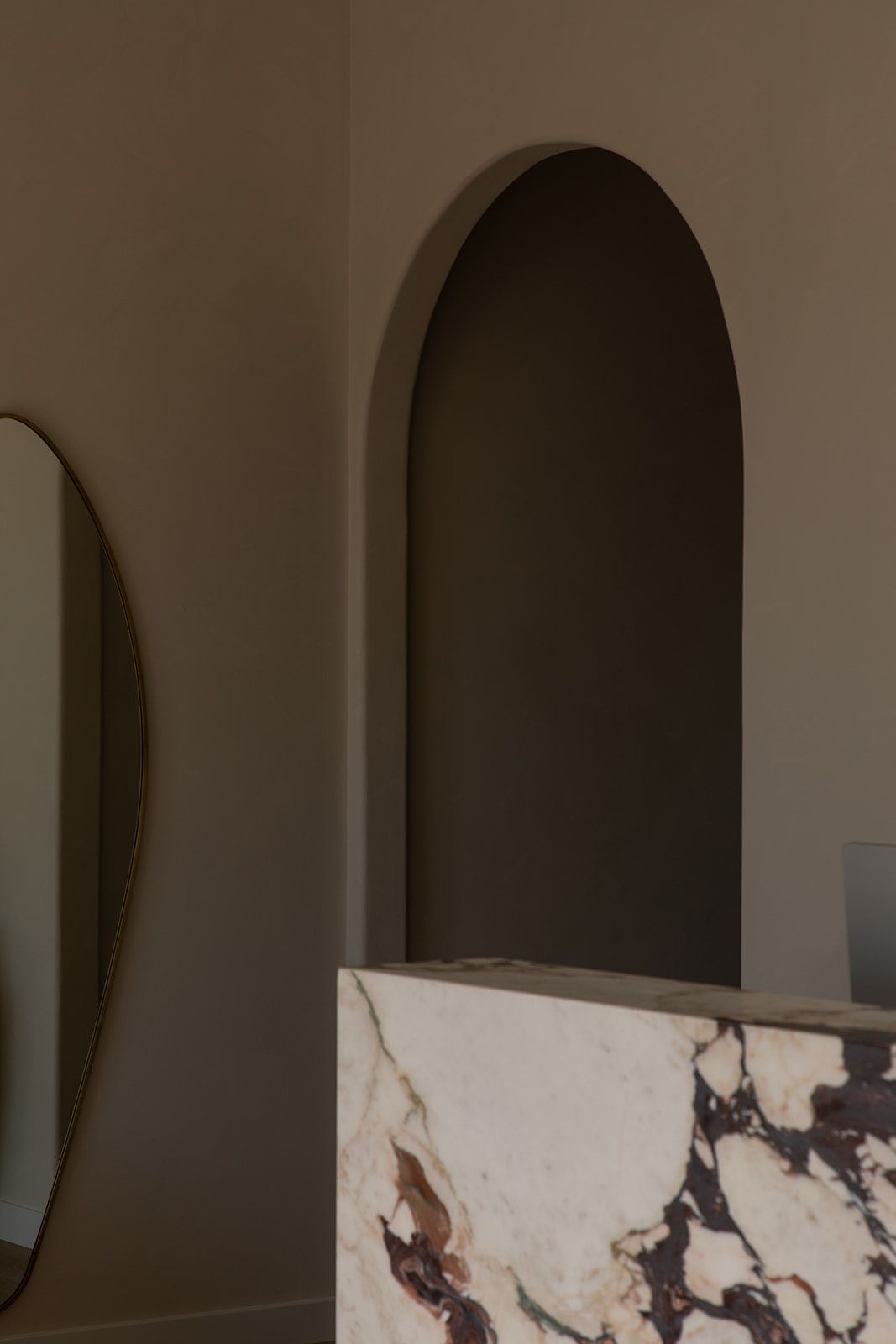 Minimalist interior featuring an arched doorway and white marble counter with dark veining patterns.