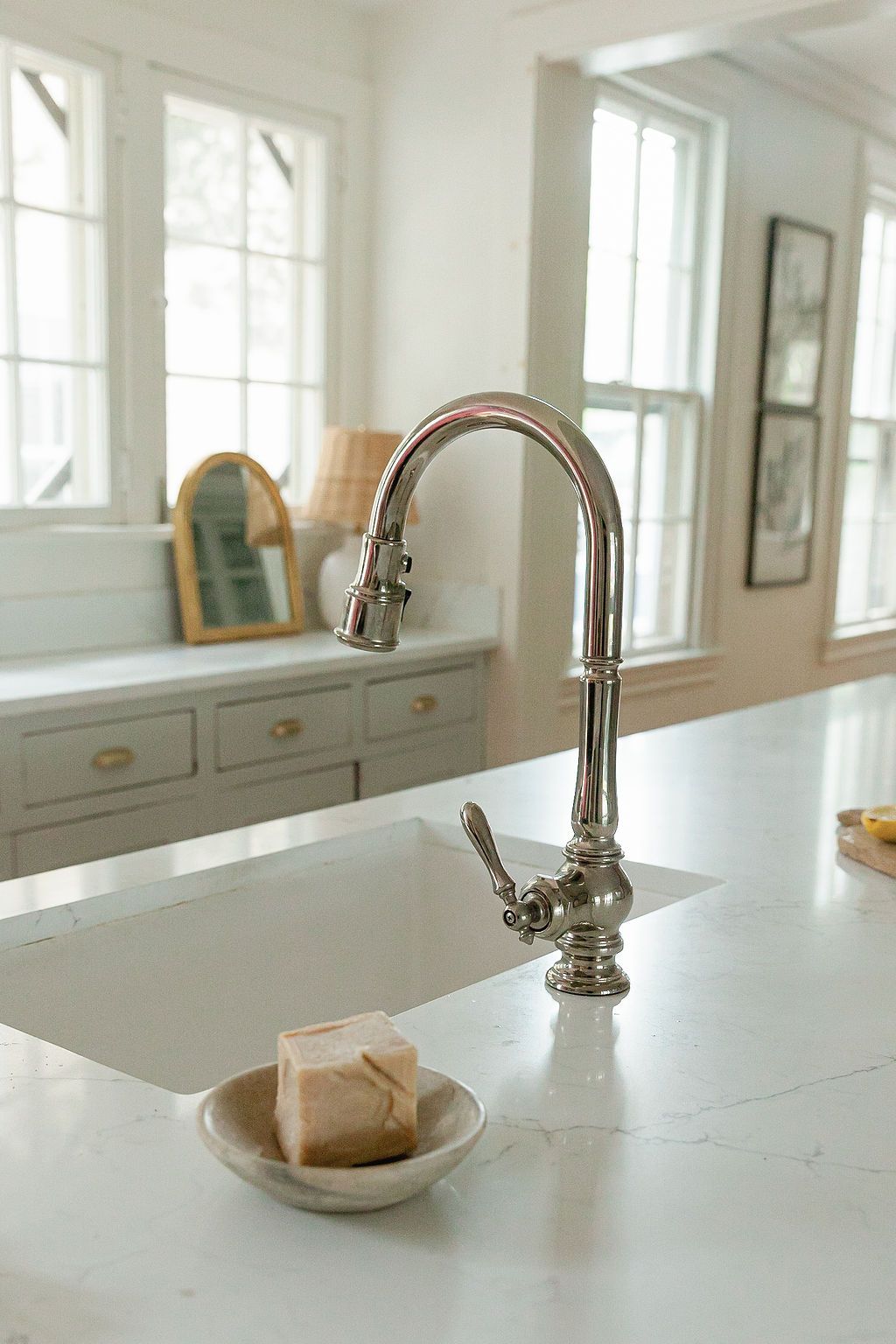 Close-up of vintage-style chrome faucet on white marble countertop with small soap dish.