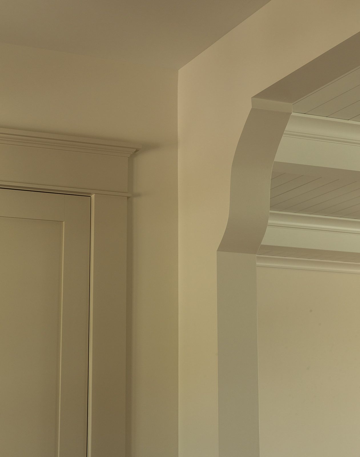 Close-up of white crown molding and arched doorway trim detail in a classic interior room.