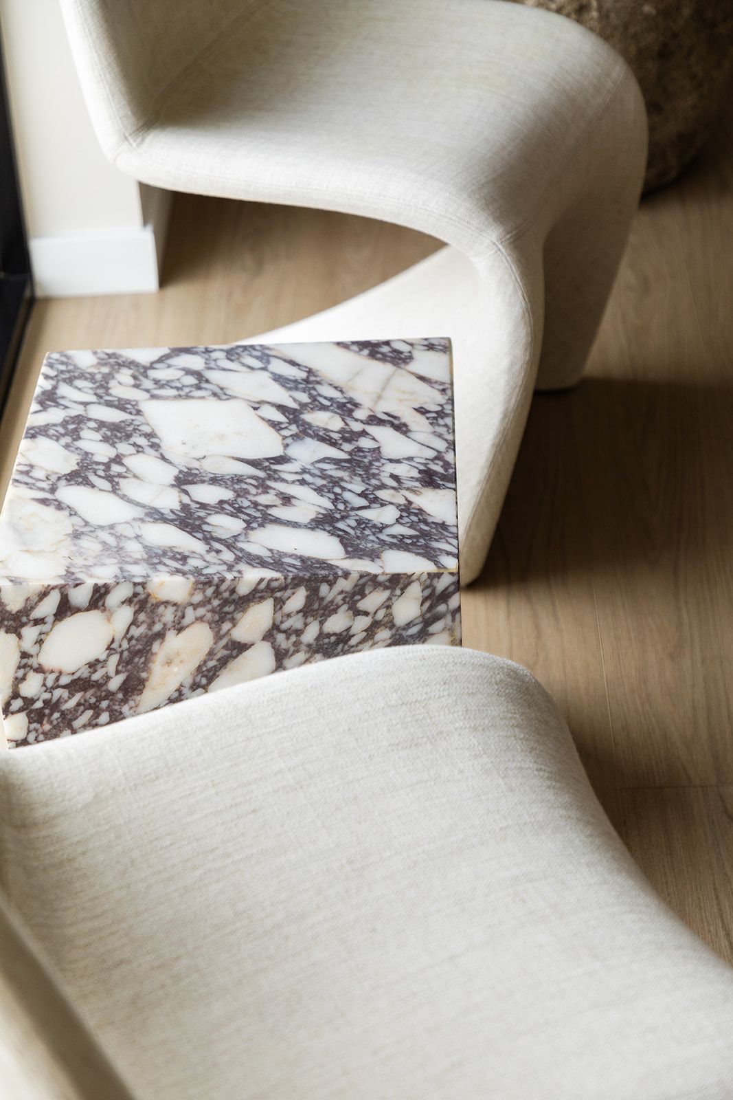 White upholstered furniture with marble accent table showing dramatic veining pattern.