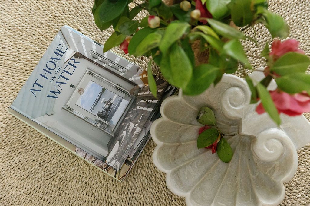 Lifestyle flatlay featuring green plants, pink flowers, and beige decor elements arranged on a woven natural texture background.