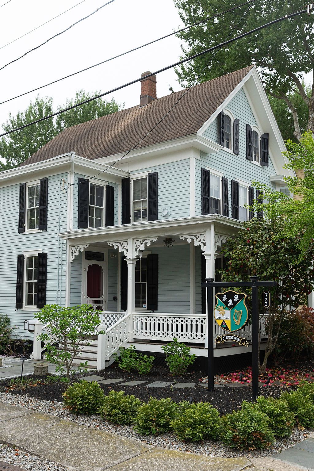 Classic white New England style house with black shutters and decorative porch trim.