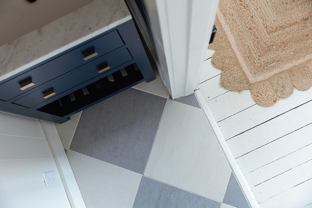 Geometric floor tiles pattern in white and gray with corner of blue vanity cabinet visible.