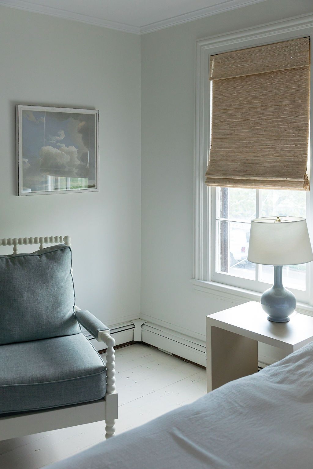 Minimalist bedroom interior with natural light streaming through windows and bamboo shades.