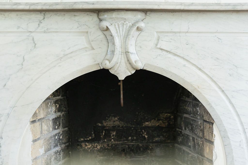 Ornate white architectural detail of a curved archway featuring decorative scrollwork and classical molding.