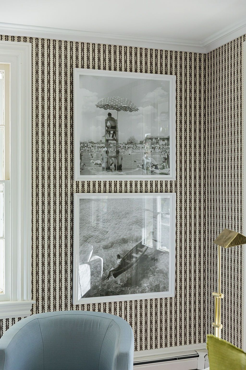 Modern living room features blue-gray seating and vintage black and white photographs displayed on patterned wallpaper walls.