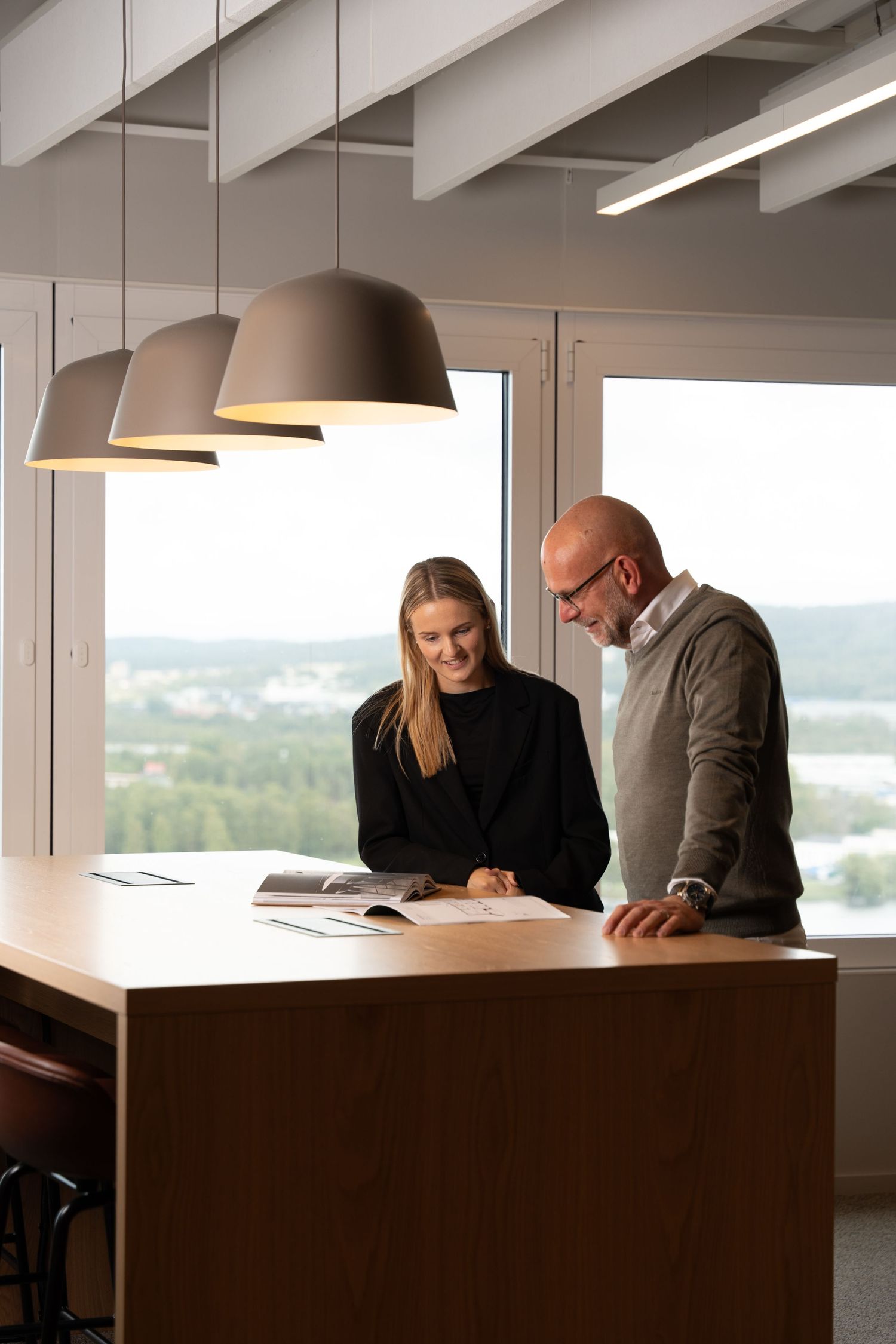 Kollegor som samarbetar vid ett skrivbord i modern kontorsmiljö.