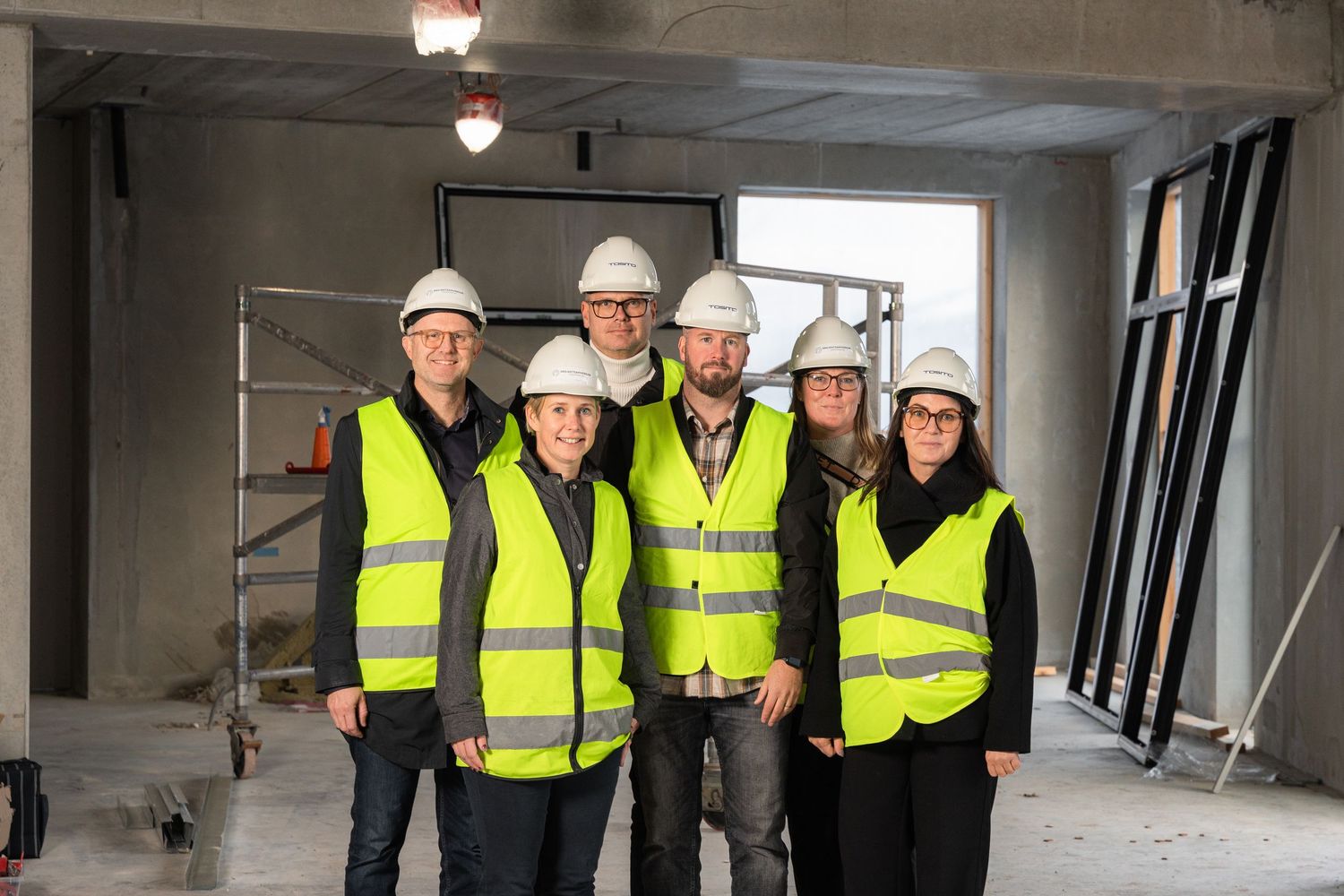 Grupporträtt av byggteam i varselvästar.