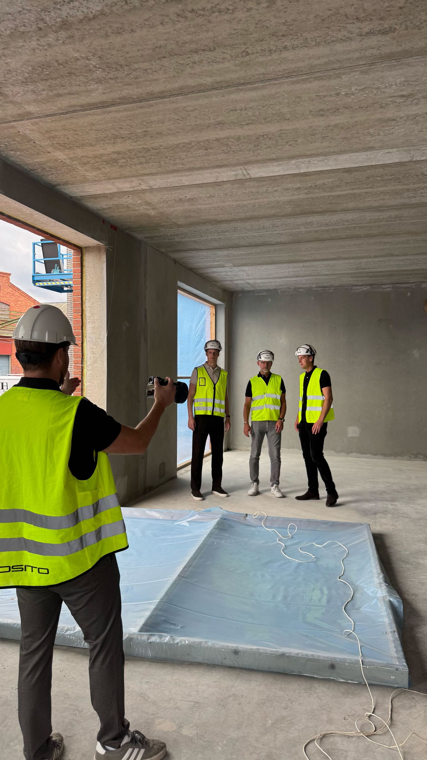 Daniel Alloh fotograferar ett team i varselvästar på en byggarbetsplats.