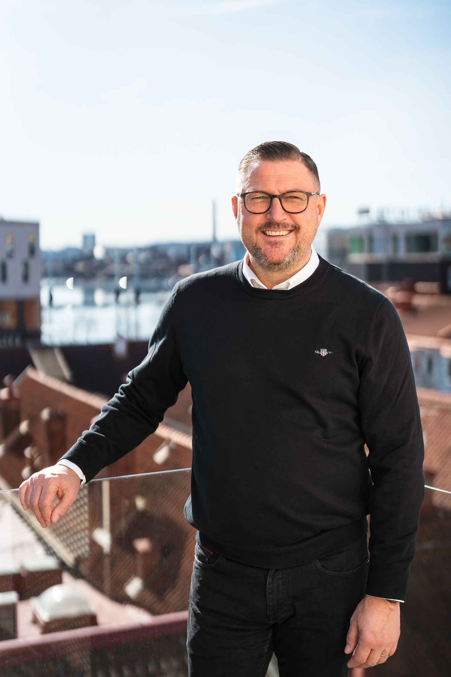 Leende man på takterrass i soligt väder.