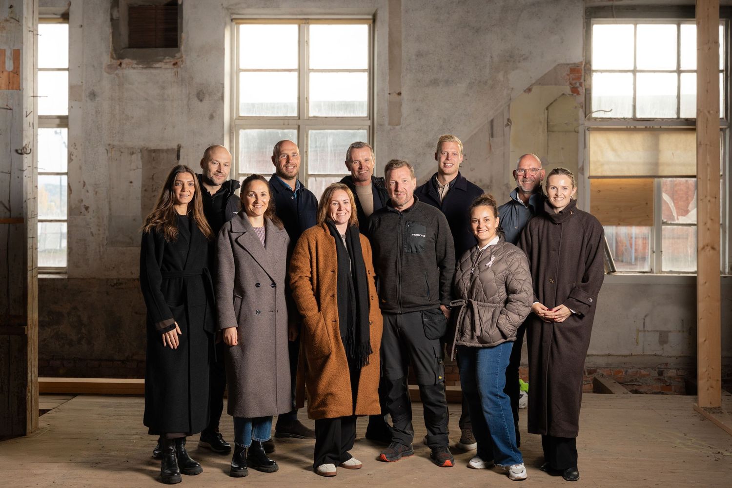Grupporträtt av elva yrkespersoner i industriell miljö.