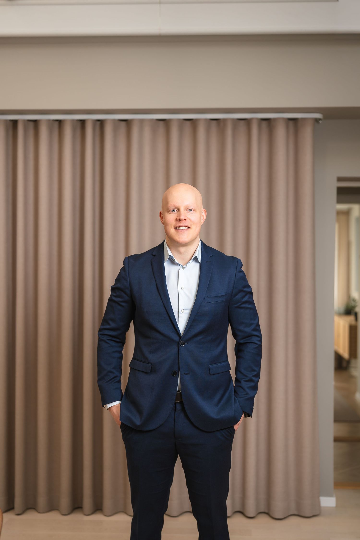 Porträtt av man i blå kostym mot ljus bakgrund.